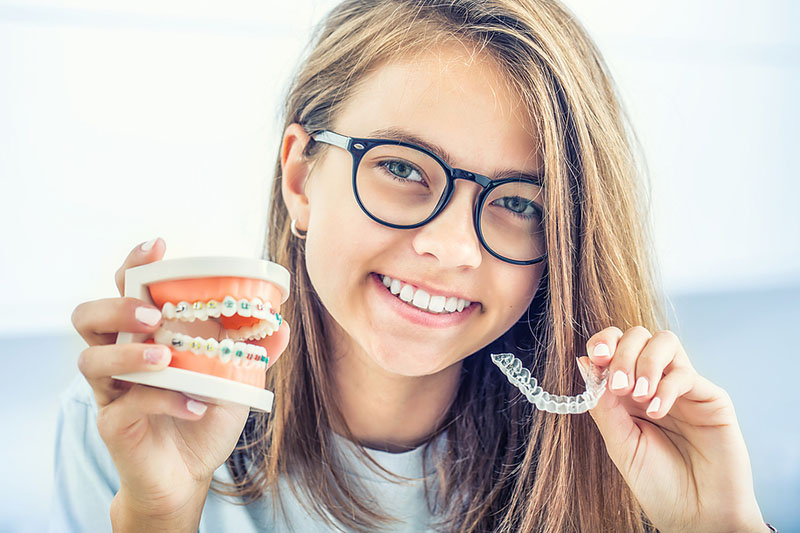 Girl smiling with invisible and metal braces