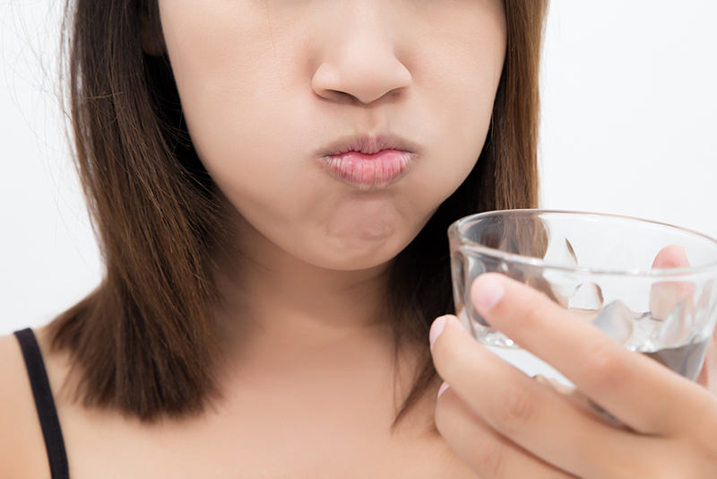 woman rinsing mouth with water after brushing teeth